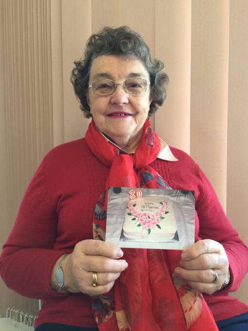 Beatrice holds a photo of her 80th birthday cake which she made for her party. Her friend Reta Beattie decorated the cake. Photo Bronwyn Haynes.